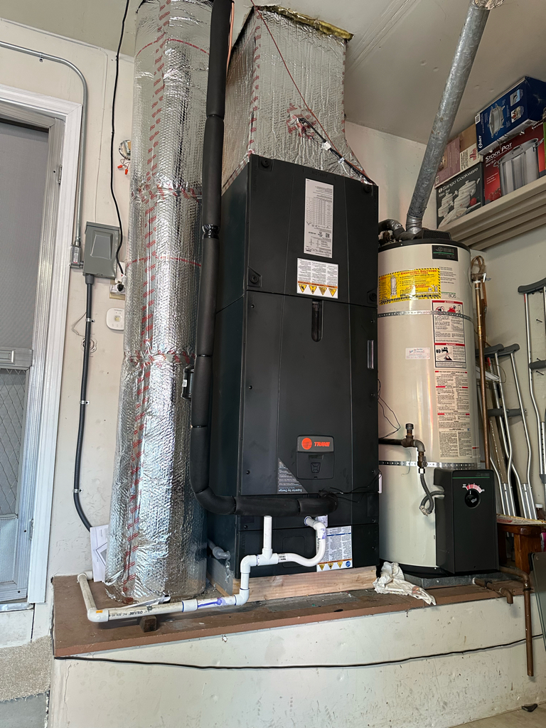 Trane central HVAC equipment installed beside a water heater in a Bay Area garage